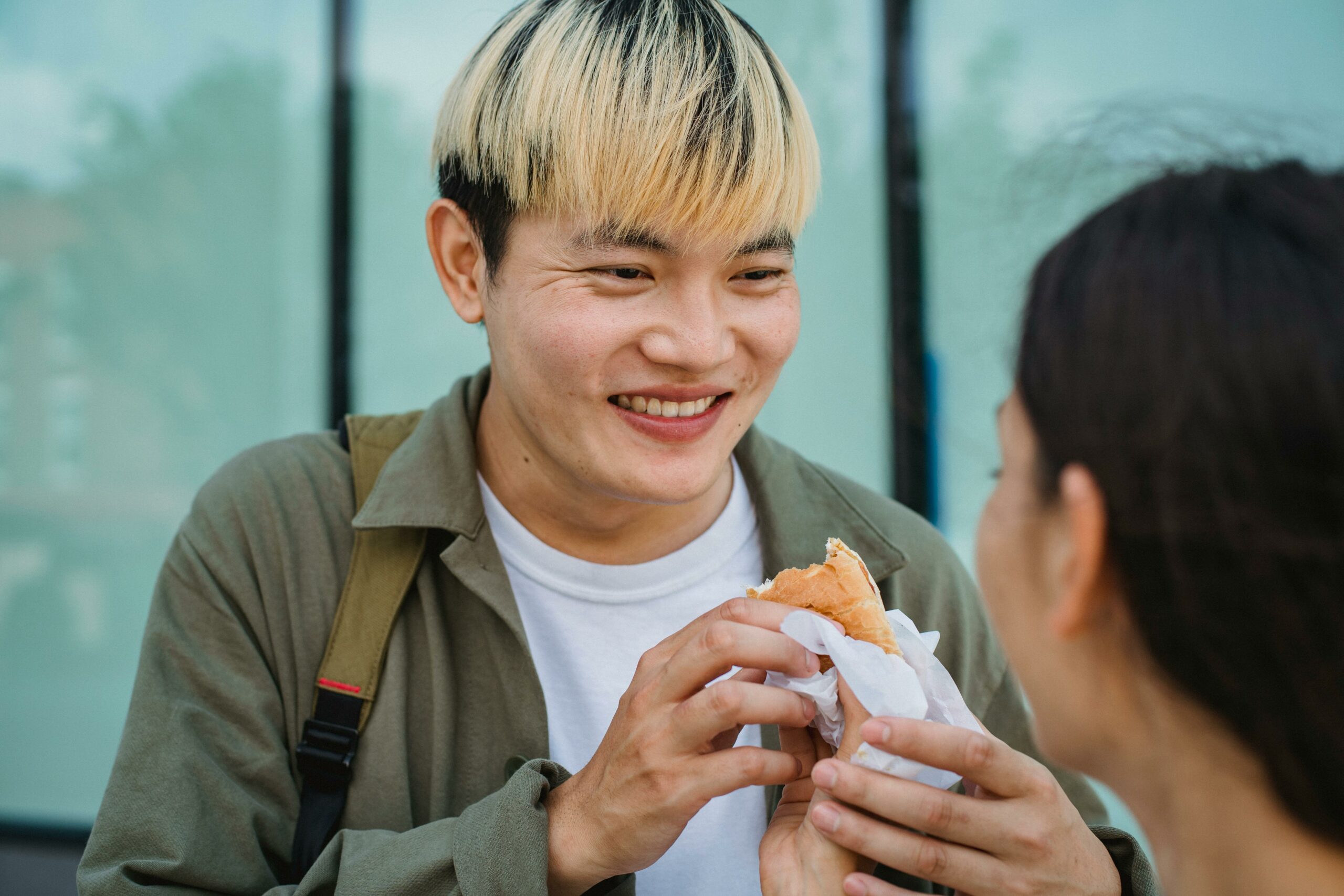 Crop Frau Hand F&uuml;ttert Fr&ouml;hlichen Asiatischen Freund Mit Hot Dog